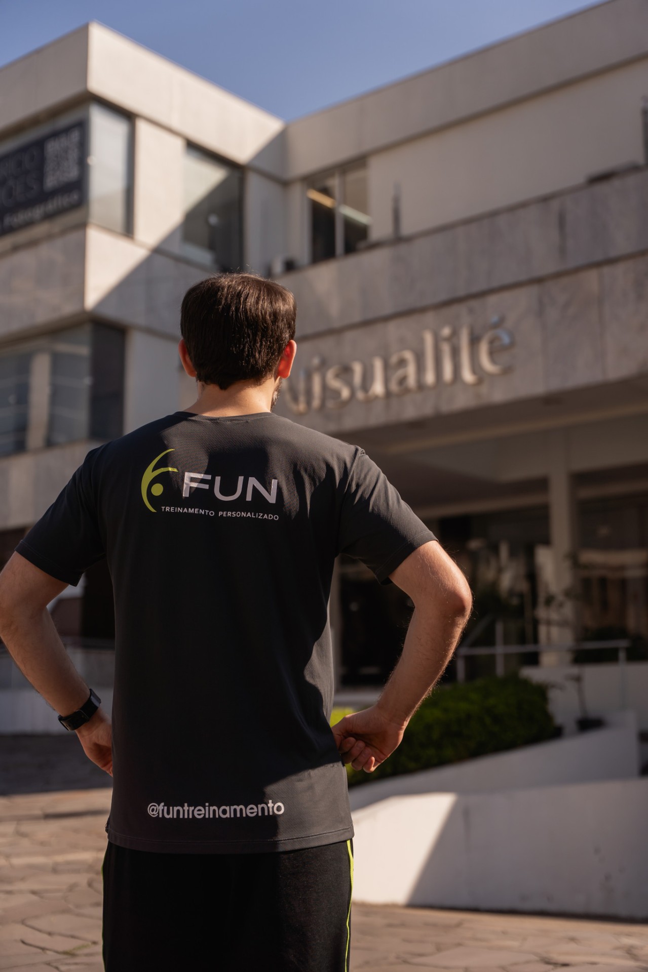 Professor com a camiseta da Fun em frente ao prédio do espaço
